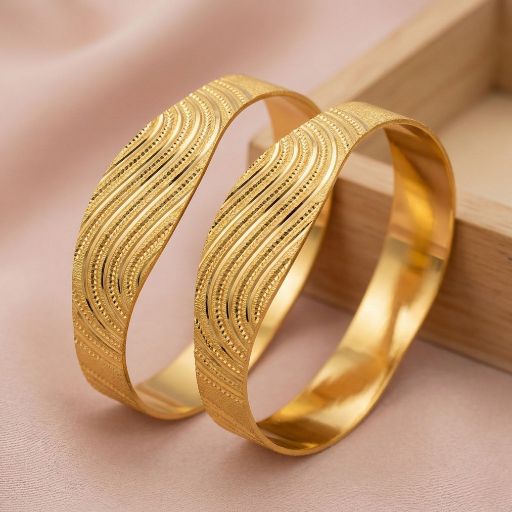 Celebrate the poetic rhythm of the tides with this stunning pair of gold-toned bangles. Featuring a masterclass in textural depth, these pieces blend fluid architectural lines with intricate engravings for a look that is both organic and opulent.